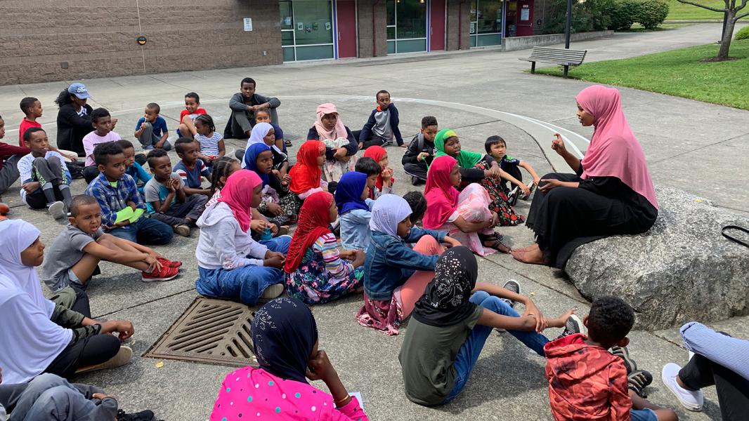 East African Community Services' students sit listening to a teacher in an outside setting, July, 2019, SeaTac, WA
