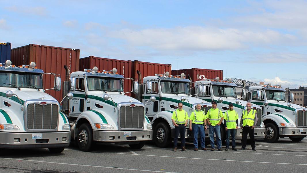 Castan empployees pose in front of big rig semi-trucks on a sunny day in south Seattle