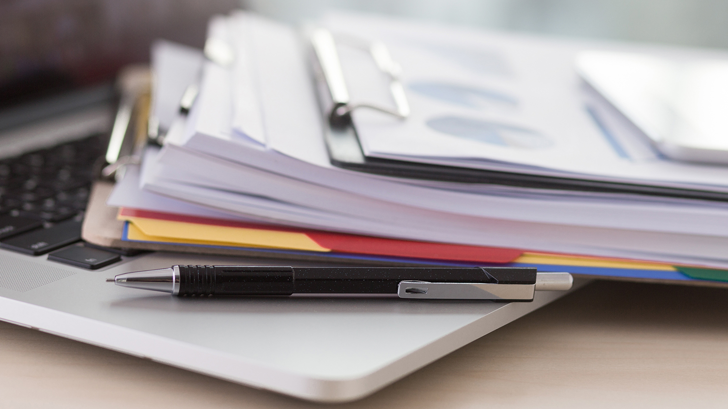 Stack of documents on the keyboard of an open laptop