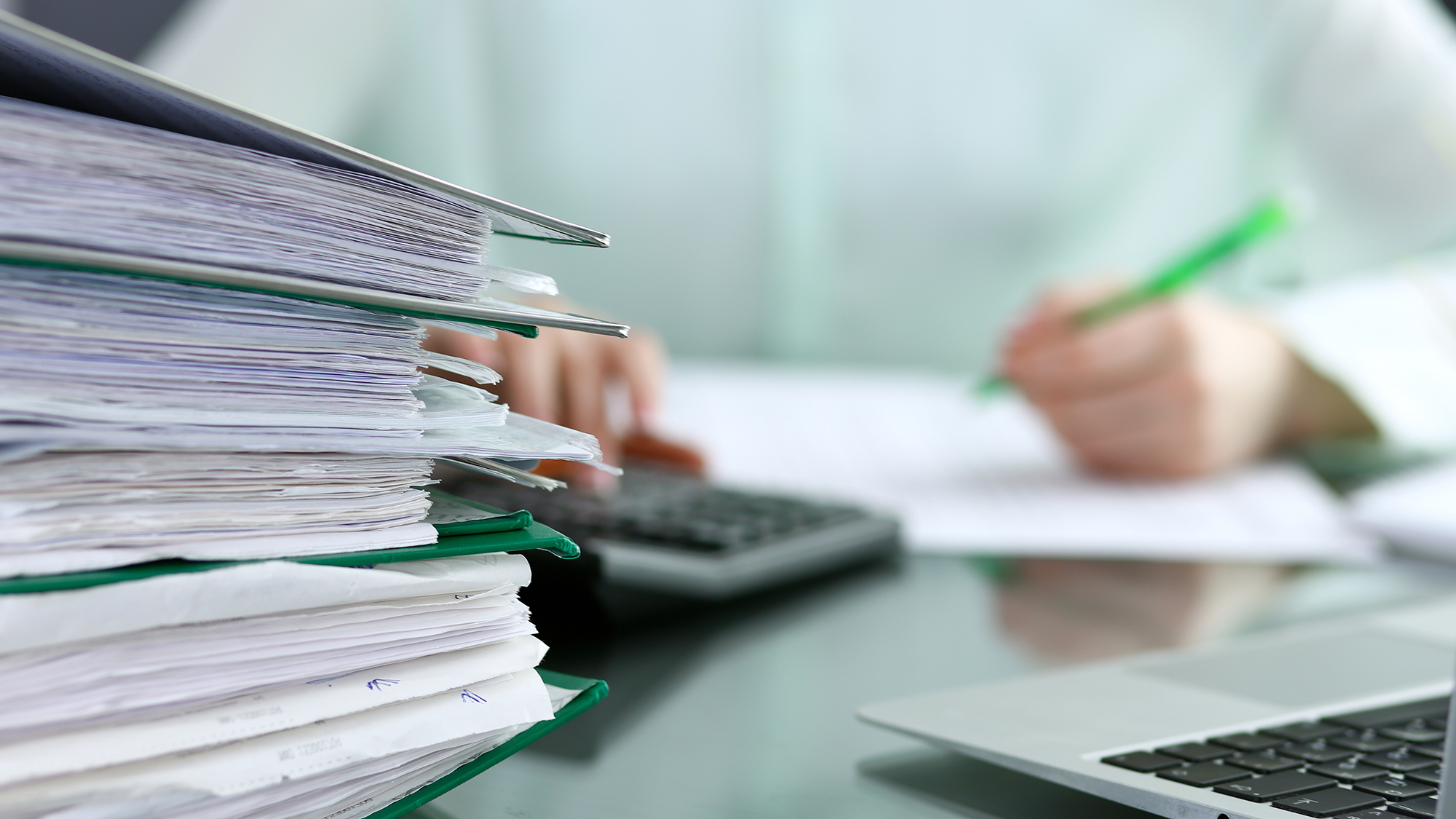 Stack of thick green file folders stuffed with pages and pages