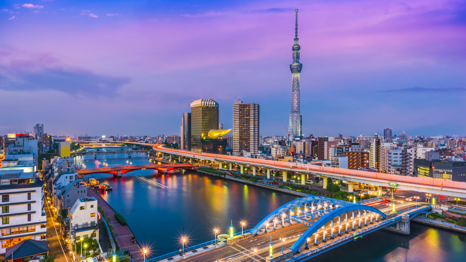 The colors of sunset off Tokyo's Sumida River highlight the art deco blue arches of Komagata Bridge, 2,080-foot-tall Tokyo Skytree building, and the golden Asahi Building.