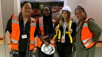 Airport employees showing off safety vests and hard hats