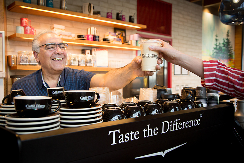 Barista hands a customer a coffee at Caffe D'arte