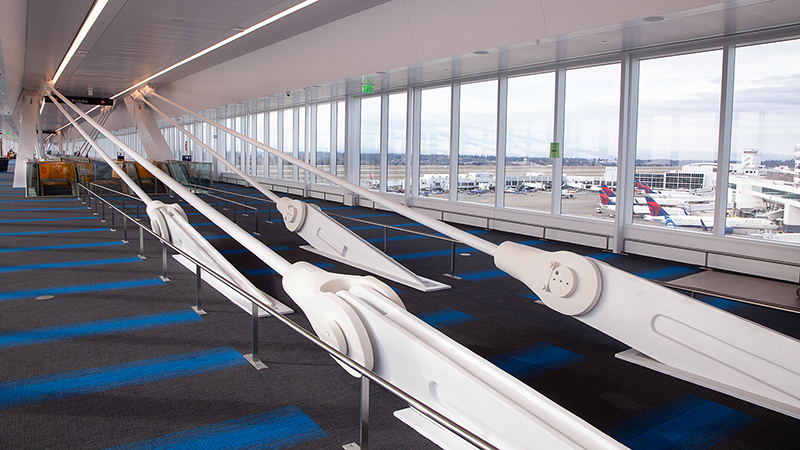 An interior view of the Pedestrian walkway at SEA that stretches over the ramp with views of the airfield and mountains
