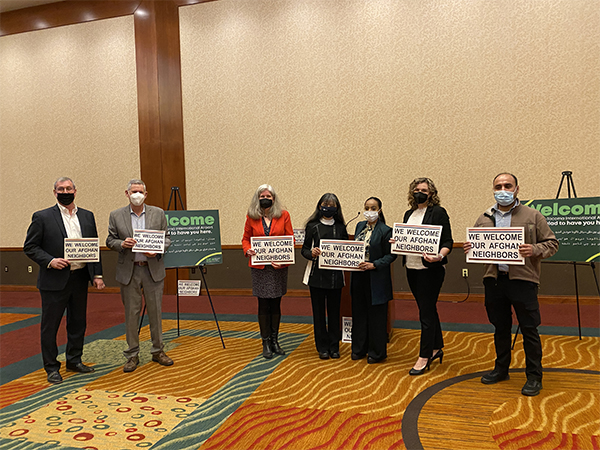 Partners including local businesses in SeaTac and state reps pose in solidartdy holding "We Welcome Our Afghan Neighbors" placards