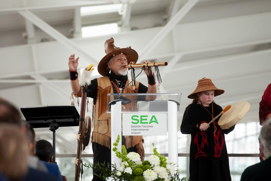 A photo of George Montero playing the flute and his granddaughter playing the drum.