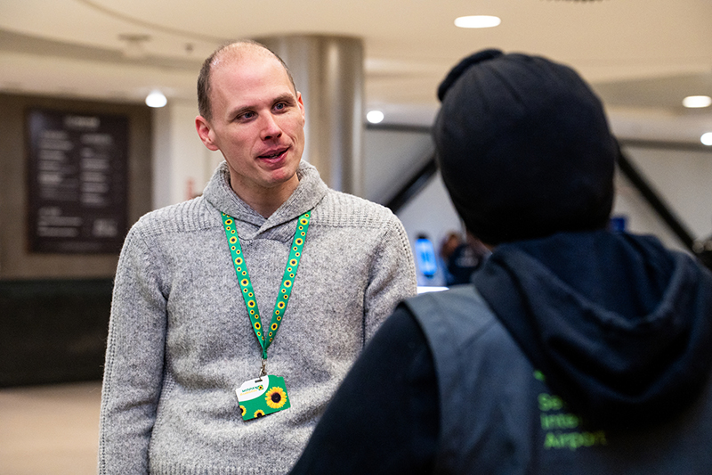 A traveler wearing a sunflower lanyard talks with an SEA employee.