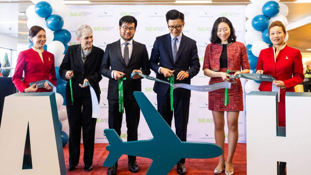 SEA Airport and Cathay Pacific representatives cut a ribbon at the inaugural nonstop flight gate event