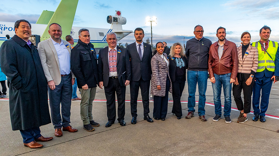 Governor Inslee with other leaders from the county, city and local municipalities pose on the airfiels at SEA with cargo planes behind filled with humanitarian supplies for Ukraine