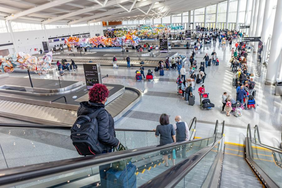 the new International Arrivals Facility (IAF) is fully open to welcome you home!  A photo of passengers collecting luggage. 