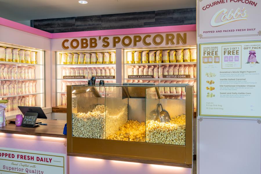 Cobb's Popcorn has glass cases filled with different popcorn flavors and shelves with pre-filled bags for purchase.