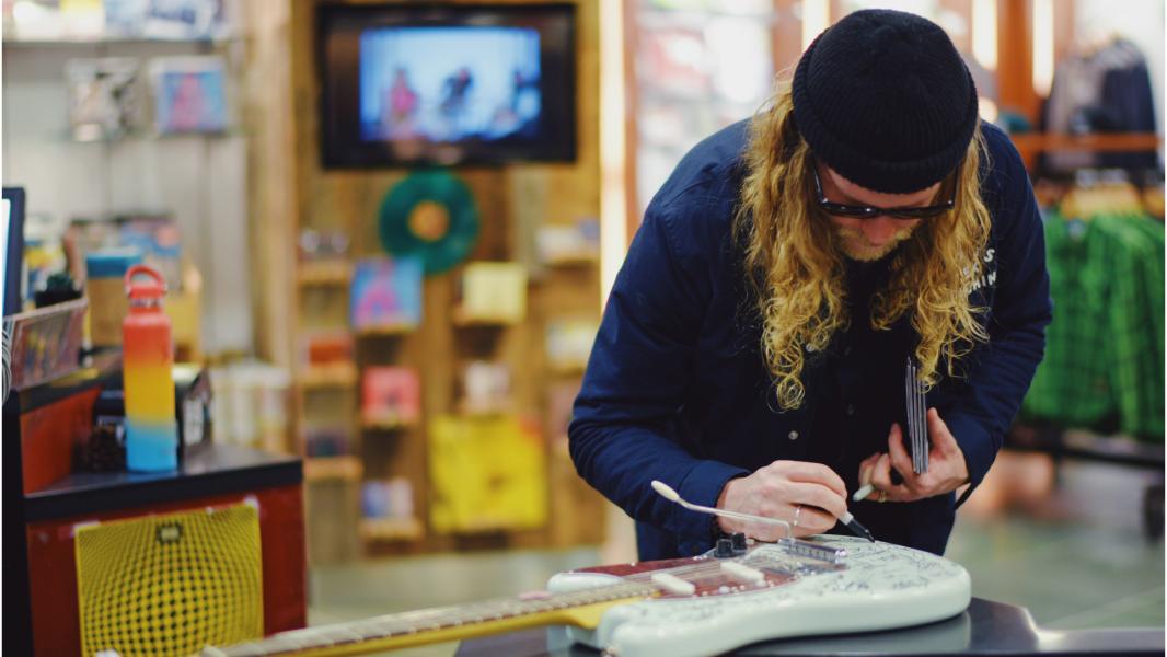 Allen Stone signs a guitar at Sub Pop records.