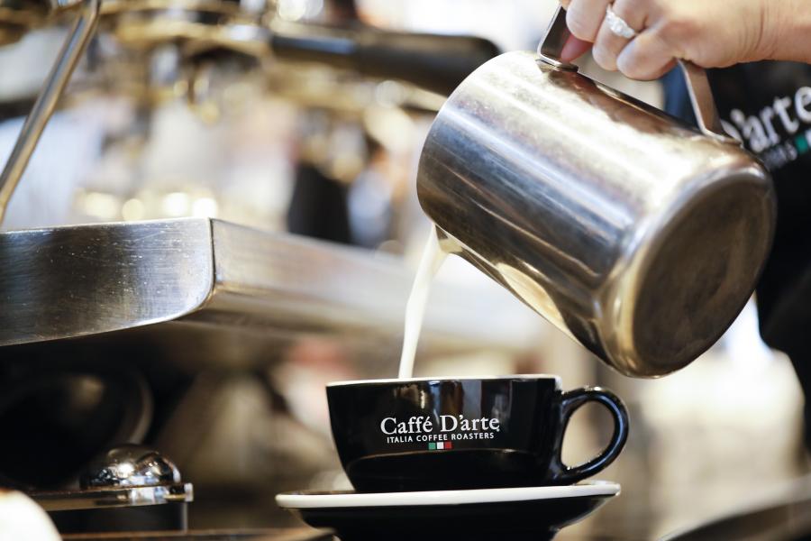 Up close shot of barista pouring milk into a latte at Caffe D'arte