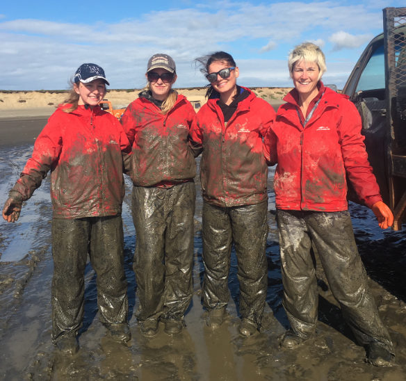 Evelyn Clark covered in mud standing next to three other women wearing fishing gear 