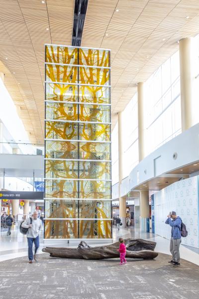 Tall glass sculpture with brass log in front
