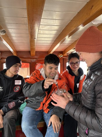 Several students work through an interactive learning station on the Adventuress.