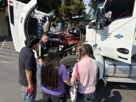 Port staff share auto mechanic skills with youth using a Port Marine Maintenance truck as a demonstration.