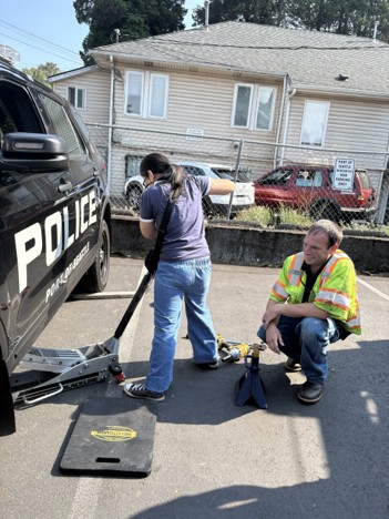 A student learns to change a flat tire on a Port vehicle.