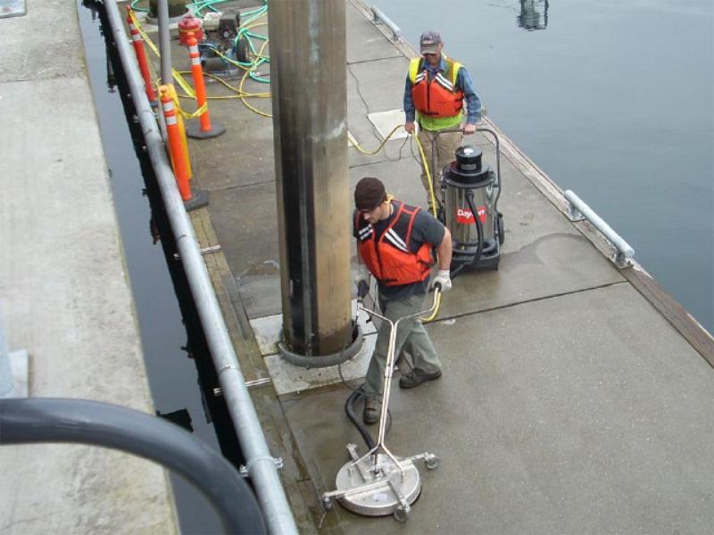 Workers cleaning dock with wash-water recovery scrubbers