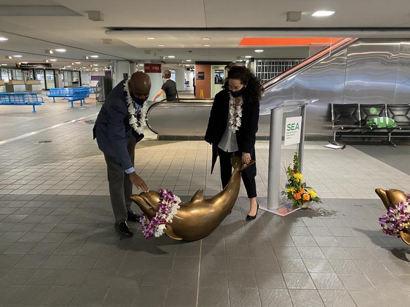 SEA Airport Director Lance Lyttle and Paige Stockley place leis on the dolphins