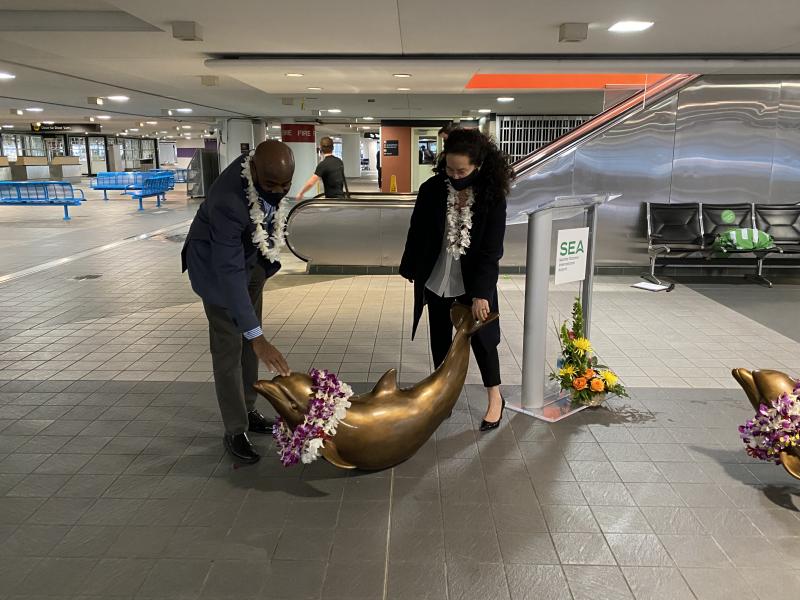 SEA Airport Director Lance Lyttle and Paige Stockley place leis on the dolphins