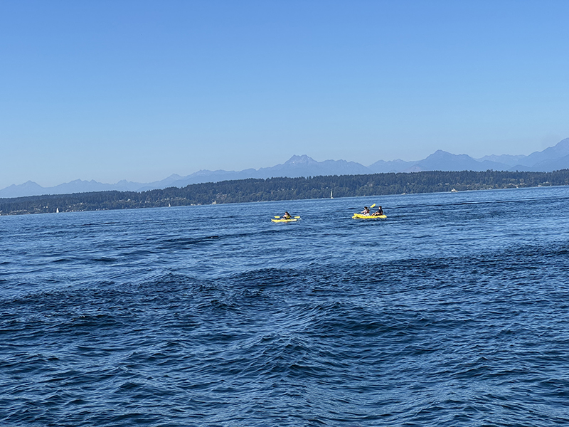 Two kayaks leaving Shilshole Bay with the Olympic Mountains in the background.