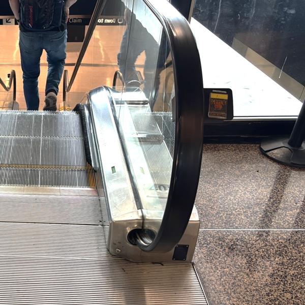 Escalator going down shows the emergency stop button located on the right