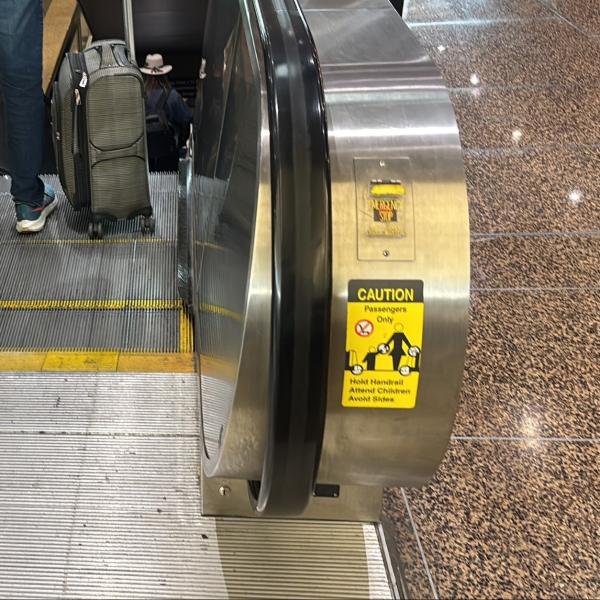 Escalator going down shows the emergency stop button located on the right