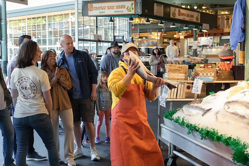 People observing the fish market on a Pike Place Market food tour