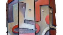 An abstract artwork made of painted, layered panels featuring curved shapes in red, gray, and blue tones.