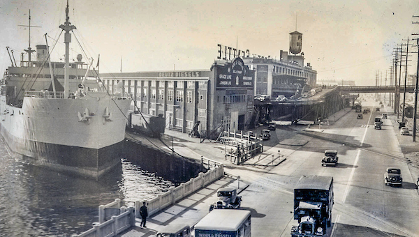 Original Port of seattle building with a large commercial ship next to it at the turn of the century