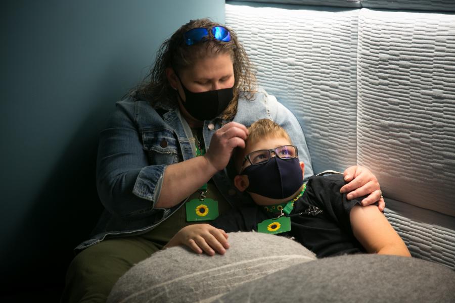 A young boy and his mother wear sunflower lanyards while lounging in the Sensory Room at SEA Airport. 