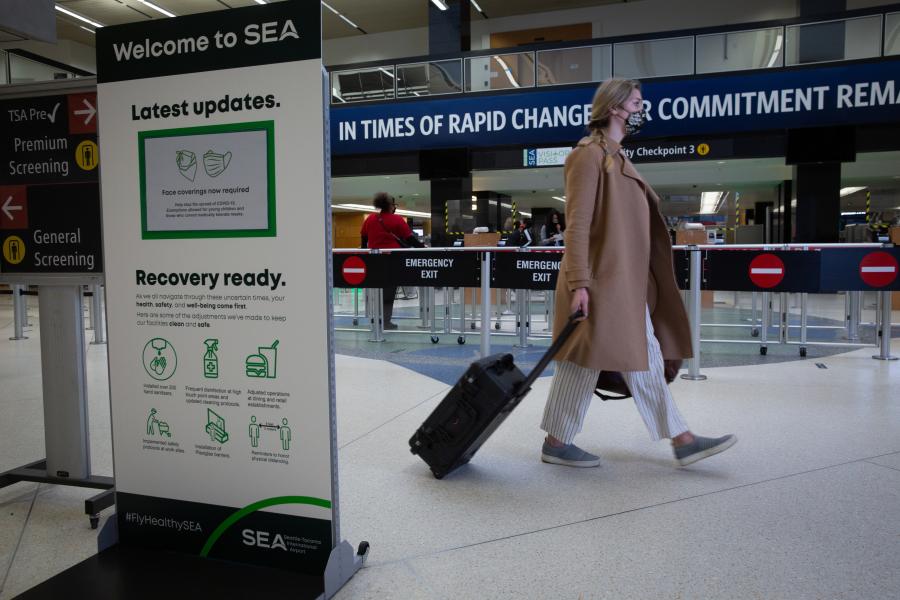 Masked passenger walks by security checkpoint at SEA Airport