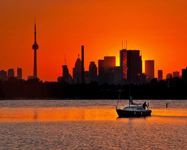 Toronto at sunset with the CN tower silhouetted and a sailboat in front