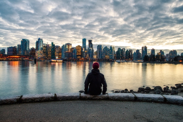 Person sitting on rock wall looking at the Vancouver Skyline