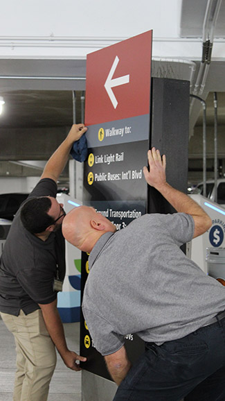Jayme and Neil install the sign in the garage.