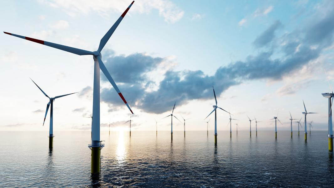 Offshore wind turbines amidst a pink-blue sky with whispy clouds and calm, reflective water