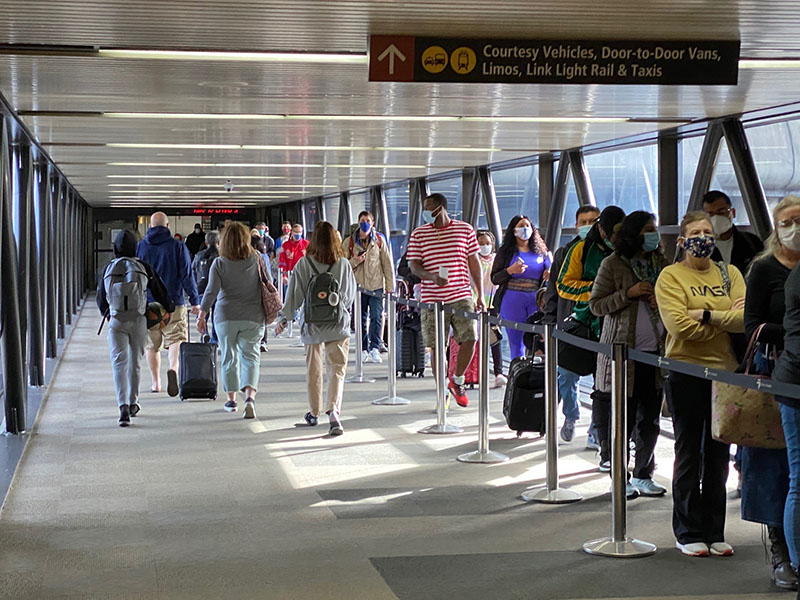 Masked passengers waiting in line in Skybridge at SEA Airport