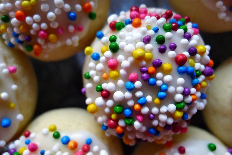 Pile of cookies with white icing and colorful sprinkles