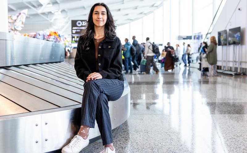 Cilicia Diaz sits by the bag carousel in the International Arrivals Facility.