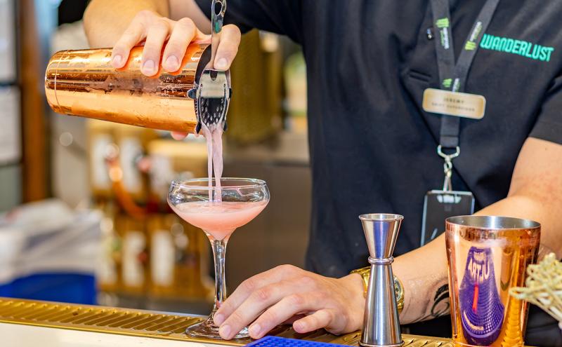 Wanderlust staff pours a Yuzu kiss into a cocktail glass.