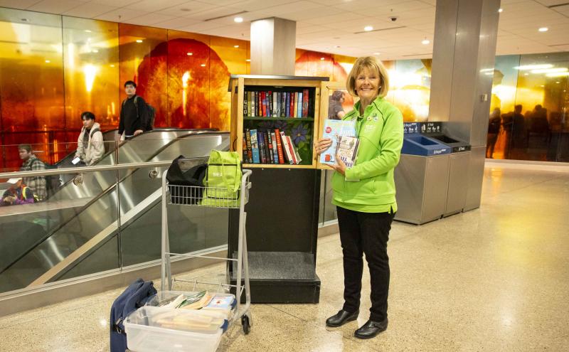 Little Free Library volunteer is smiling and restocking the library 