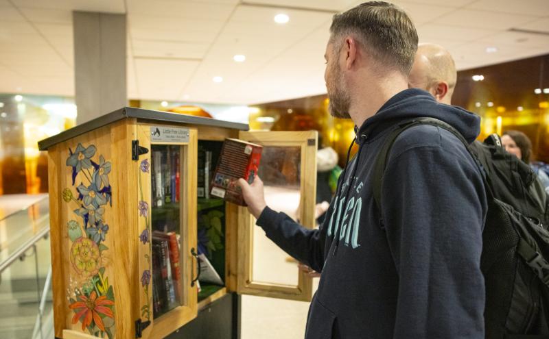 Two travelers peruse the Little Free Library offerings