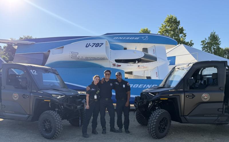 three port of seattle firefighters stand between two atvs and a trailer laoded hydroplane smiling