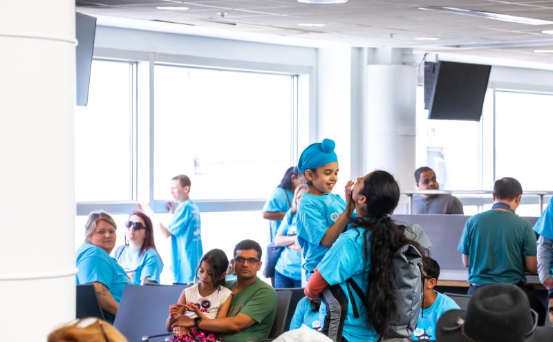 Parent and child in blue Wings for All shirts hug and smile in the gate area