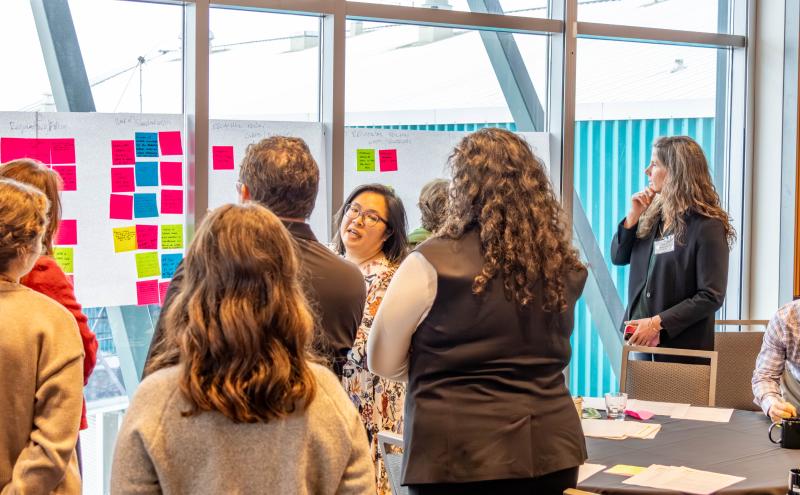 Group of participants gather around post it notes on a window. 