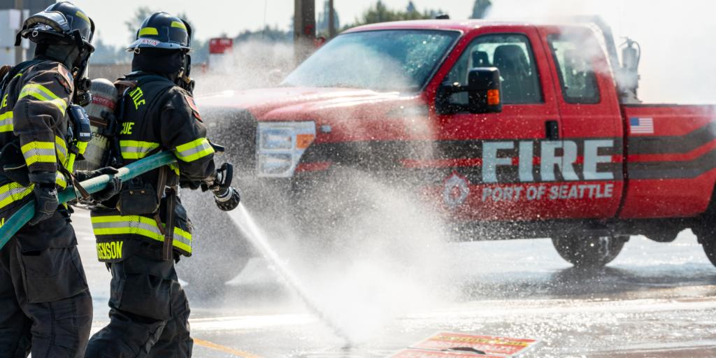 Port of Seattle Fire Department firefighters conducting a fire exercise putting out an electrical vehicle fire on a test vehicle