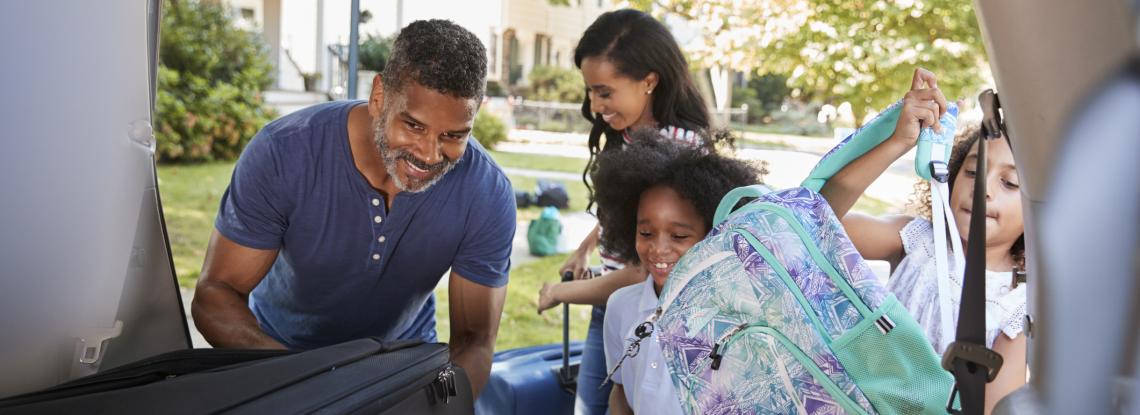 Family loading luggage into back of their car.