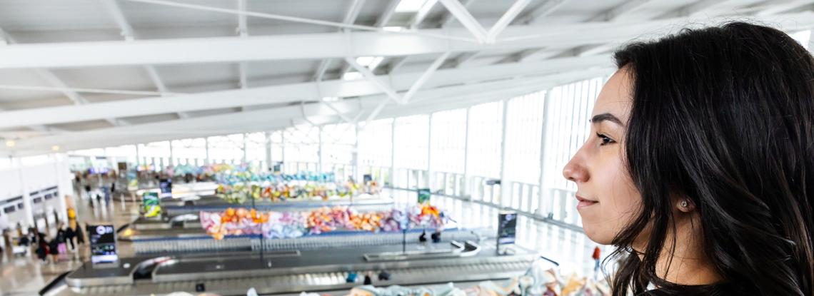 Cilicia Diaz, SEA intern, looks down at the baggage carousels in the International Arrivals Facility