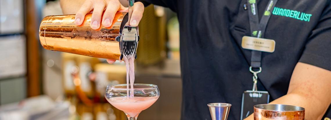 Wanderlust staff pours a Yuzu kiss into a cocktail glass.